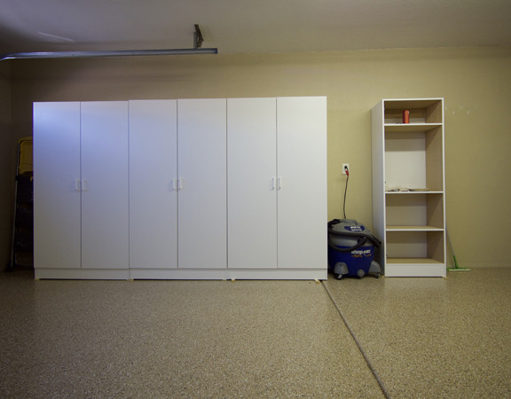 This image shows a garage floor with flake epoxy painted floor. There are cabinets on the wall.