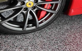 This image shows a flake epoxy floor. A red car is parked there.